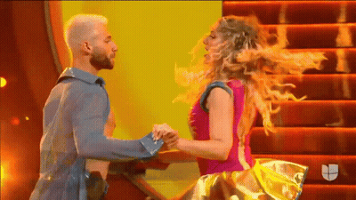 A Man And A Woman Are Dancing On A Stage And The Woman Is Wearing A Pink Dress . GIF