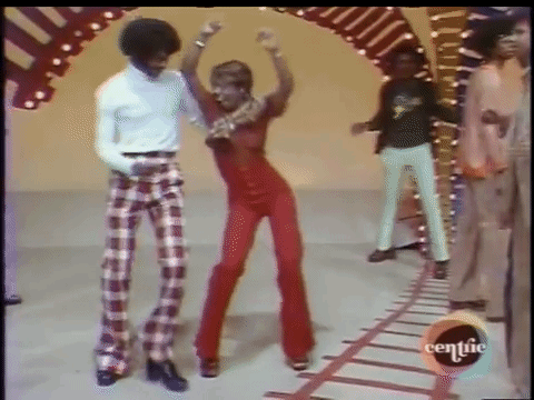 A Man And A Woman Are Dancing On A Stage In Front Of A Crowd Of People . GIF