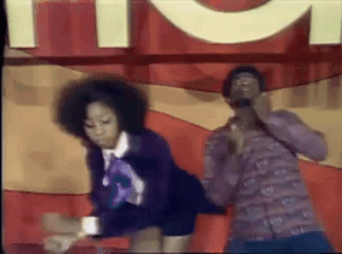 A Man And A Woman Are Dancing On A Stage In Front Of A Sign . GIF