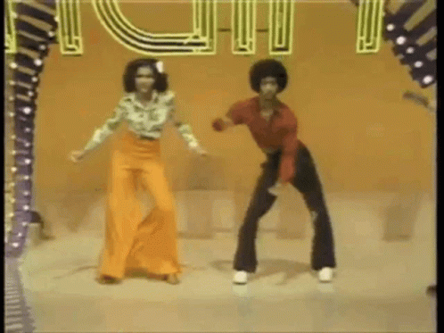A Man And A Woman Are Dancing On A Stage In Front Of A Sign . GIF