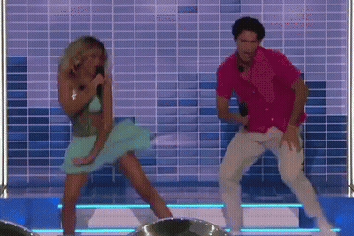A Man And A Woman Are Dancing On A Stage In Front Of A Tiled Wall . GIF