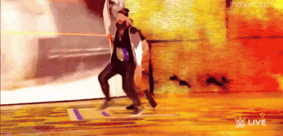 A Man And A Woman Are Dancing On A Stage In Front Of A Wall . GIF