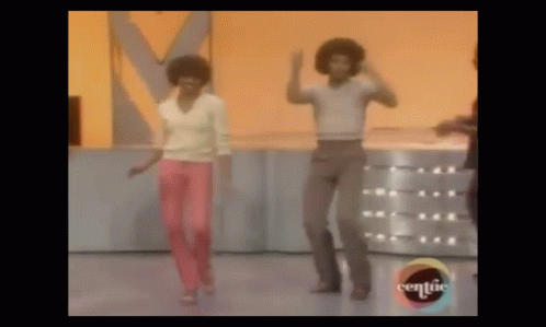 A Man And A Woman Are Dancing On A Stage . The Woman Is Wearing Pink Pants . GIF