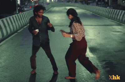 A Man And A Woman Are Dancing On A Street With Xhk Written In The Corner GIF