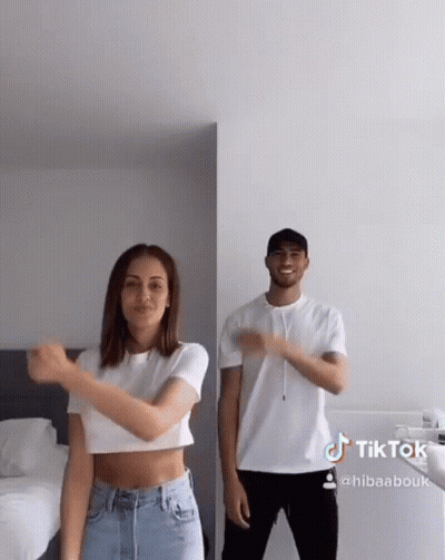 A Man And A Woman Are Dancing Together In A Bedroom . The Woman Is Wearing A Crop Top . GIF