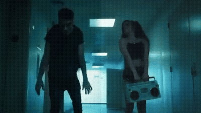 A Man And A Woman Are Dancing Together In A Hallway In A Dark Room . GIF