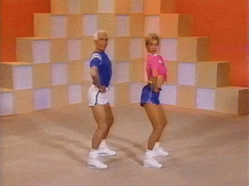 A Man And A Woman Are Dancing Together In Front Of A Checkered Wall GIF