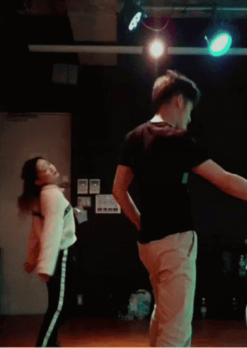 A Man And A Woman Are Doing A Trick In Front Of A Sign That Says Play The Game GIF