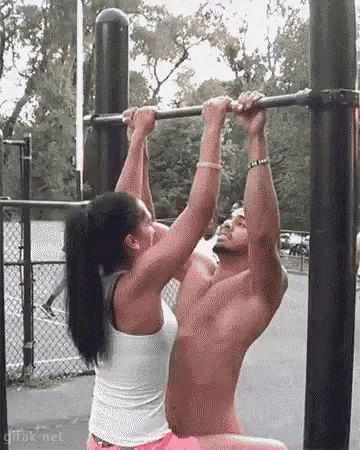 A Man And A Woman Are Doing Pull Ups Together On A Bar . GIF