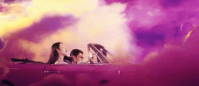 A Man And A Woman Are Driving A Purple Convertible Car . GIF