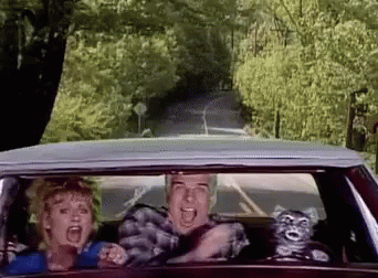 A Man And A Woman Are Driving Down A Road In A Car GIF