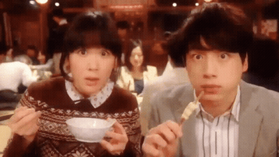 A Man And A Woman Are Eating Food With Chopsticks And A Bowl Of Soup . GIF