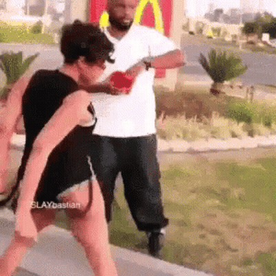 A Man And A Woman Are Fighting In Front Of A Mcdonald 'S . GIF