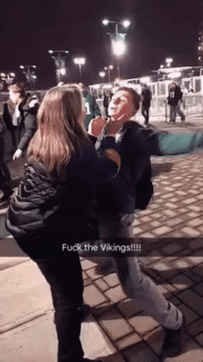A Man And A Woman Are Fighting With The Words Fuck The Vikings On The Bottom Right GIF
