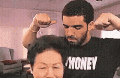 A Man And A Woman Are Flexing Their Muscles In A Living Room . GIF