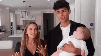 A Man And A Woman Are Holding A Baby In A Kitchen . GIF