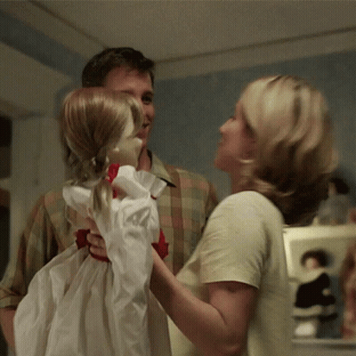 A Man And A Woman Are Holding A Little Girl Doll GIF