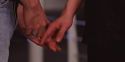 A Man And A Woman Are Holding Hands And The Woman Has A Wedding Ring On Her Finger . GIF