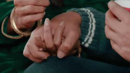 A Man And A Woman Are Holding Hands And The Woman Is Wearing A Ring On Her Finger . GIF