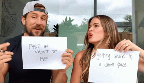 A Man And A Woman Are Holding Up Signs That Say Fart In Front Of Me And Getting Stuck In A Small Space GIF