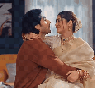 A Man And A Woman Are Hugging And Kissing In A Room . GIF