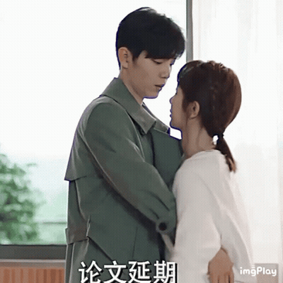 A Man And A Woman Are Hugging And Kissing In Front Of A Window With Chinese Writing On The Bottom GIF