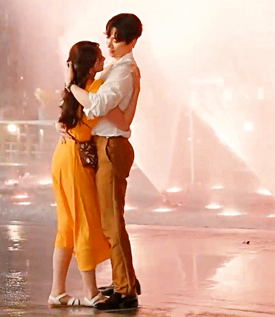 A Man And A Woman Are Hugging And Kissing On A Wet Floor GIF
