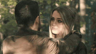 A Man And A Woman Are Hugging And Looking At Each Other In The Woods . GIF