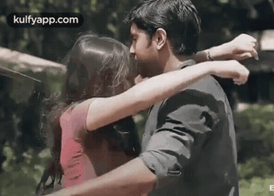 A Man And A Woman Are Hugging Each Other And Kissing . GIF