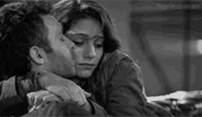 A Man And A Woman Are Hugging Each Other And Kissing . GIF