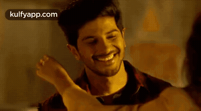 A Man And A Woman Are Hugging Each Other And Smiling . The Woman Is Wearing A Yellow Shirt . GIF