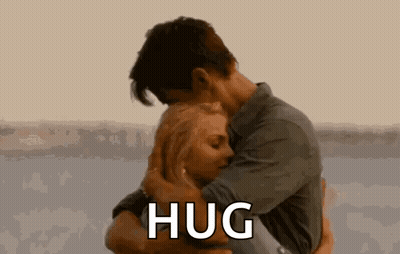 A Man And A Woman Are Hugging Each Other And The Man Is Saying `` Hug '' . GIF