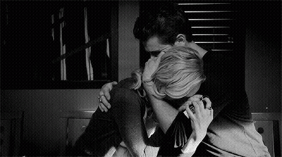 A Man And A Woman Are Hugging Each Other In A Black And White Photo GIF