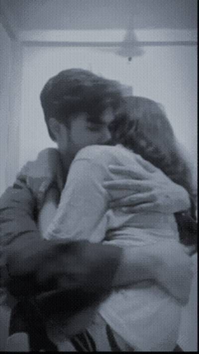 A Man And A Woman Are Hugging Each Other In A Black And White Photo GIF