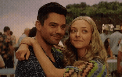A Man And A Woman Are Hugging Each Other In A Crowded Area . GIF