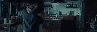 A Man And A Woman Are Hugging Each Other In A Kitchen . GIF