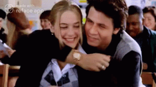 A Man And A Woman Are Hugging Each Other In A Room . GIF
