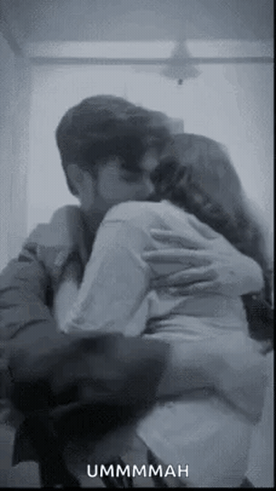 A Man And A Woman Are Hugging Each Other In A Room . GIF
