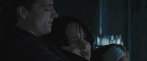 A Man And A Woman Are Hugging Each Other In The Dark . GIF