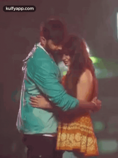 A Man And A Woman Are Hugging Each Other In The Dark . GIF