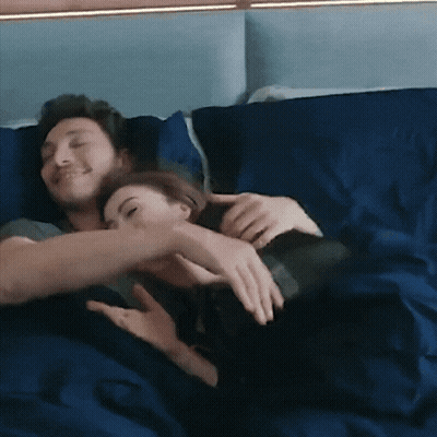 A Man And A Woman Are Hugging Each Other On A Bed GIF