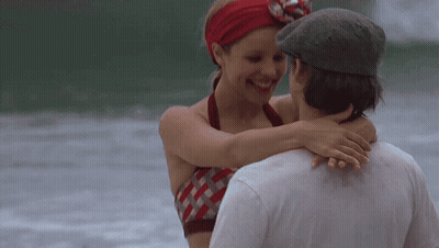 A Man And A Woman Are Hugging Each Other On The Beach GIF