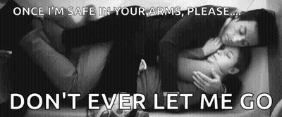 A Man And A Woman Are Hugging Each Other While Laying On A Bed . GIF