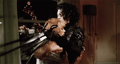 A Man And A Woman Are Hugging Each Other With A Christmas Tree In The Background Behind Them GIF