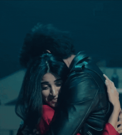 A Man And A Woman Are Hugging In A Dark Room GIF