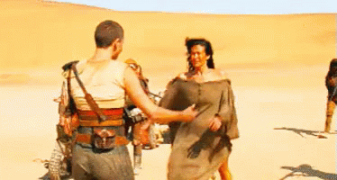 A Man And A Woman Are Hugging In The Middle Of A Desert . GIF