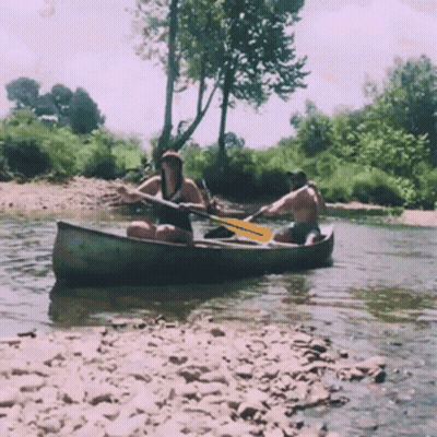 A Man And A Woman Are In A Canoe In A River GIF