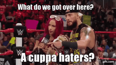 A Man And A Woman Are In A Wrestling Ring And The Man Is Pointing At The Woman Who Is Holding A Trophy . GIF