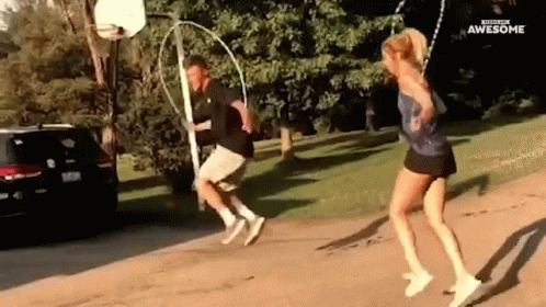 A Man And A Woman Are Jumping A Rope In Front Of A Basketball Net . GIF