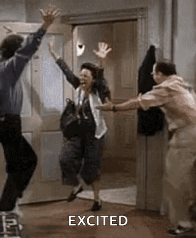 A Man And A Woman Are Jumping In The Air In A Room With Their Arms In The Air . GIF
